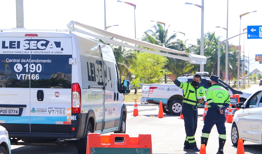 a foto mostra a van da lei seca da amc e dois agentes ao lado dela em uma blitz do órgão